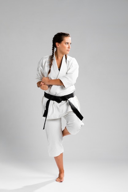 Mujer en posición de combate vistiendo el uniforme blanco sobre fondo gris