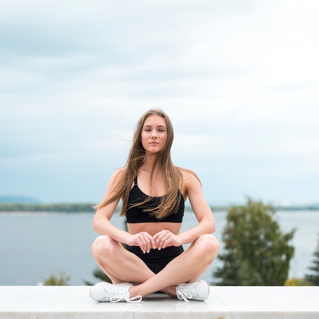 Mujer en posición de yoga mirando la cámara de tiro largo