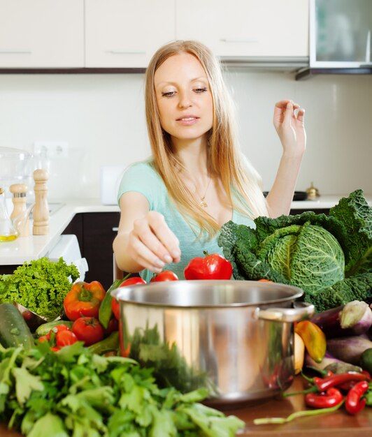 Mujer positiva cocinar de verduras crudas