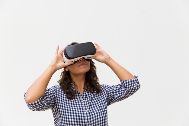 Mujer positiva con gafas de realidad virtual, disfrutando de la experiencia