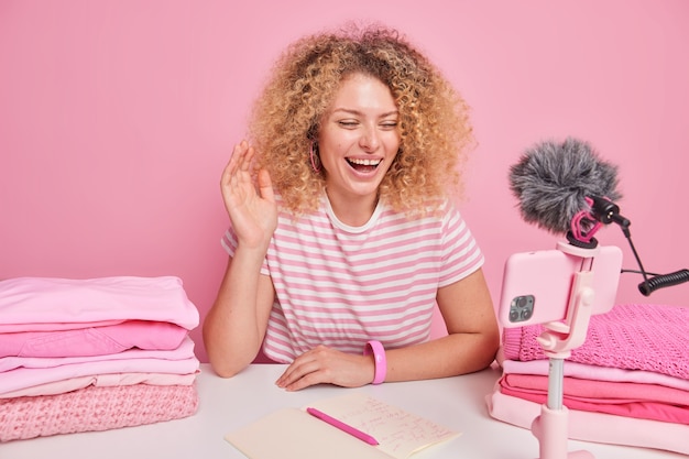 Mujer positiva con ondas de pelo rizado Hola a cámara