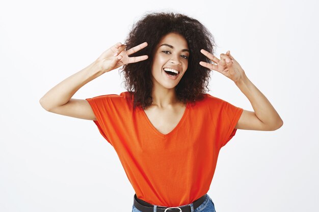 mujer positiva con peinado afro posando en el estudio