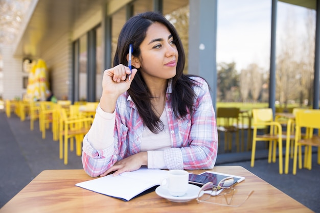 Mujer positiva que hace notas en café al aire libre