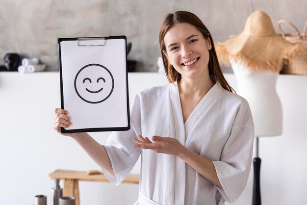 Mujer positiva que sostiene el portapapeles con cara sonriente