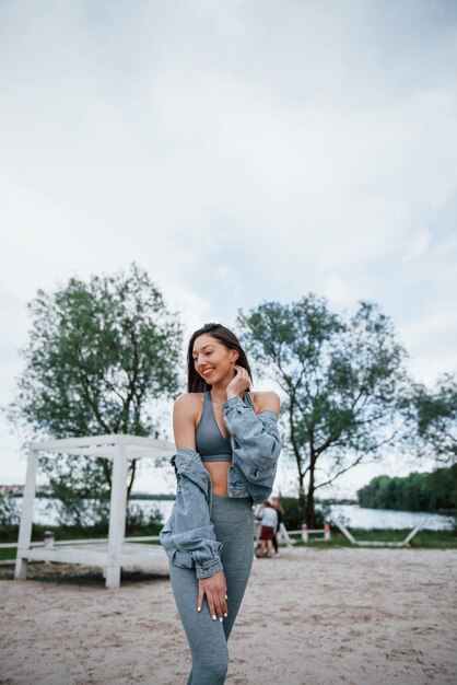 Mujer positiva en ropa deportiva disfrutando de la naturaleza en la playa