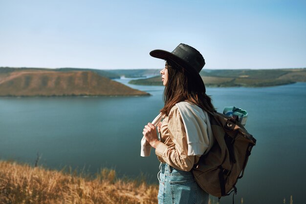 Mujer positiva con sombrero de vaquero caminando en el área de bakota