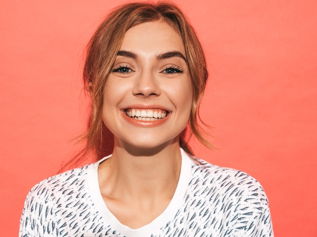 Mujer positiva sonriendo. Modelo divertido que presenta cerca de la pared rosada en estudio