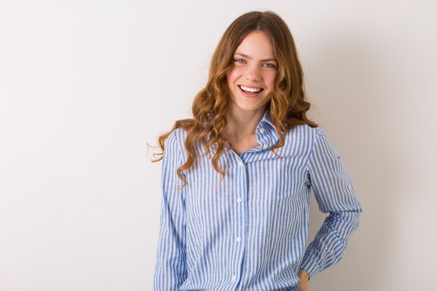 Mujer positiva sonriendo sinceramente, joven dama de aspecto natural de edad estudiantil vistiendo camisa de algodón azul