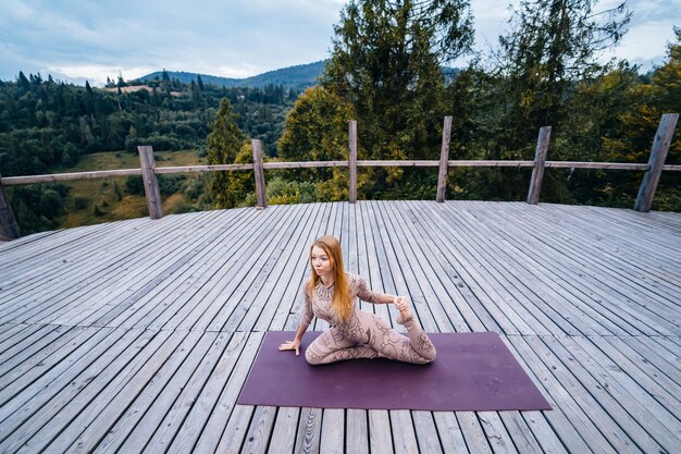 Una mujer practica yoga por la mañana en una terraza al aire libre.