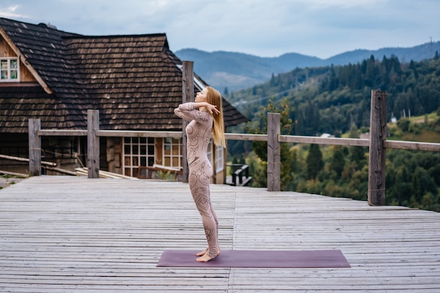 Una mujer practica yoga por la mañana en una terraza al aire libre.