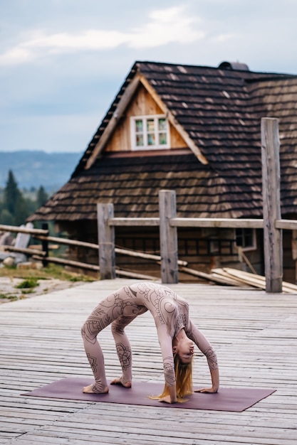 Una mujer practica yoga por la mañana en una terraza al aire libre.