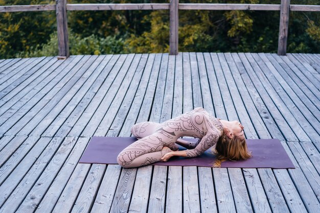 Una mujer practica yoga por la mañana en una terraza al aire libre.