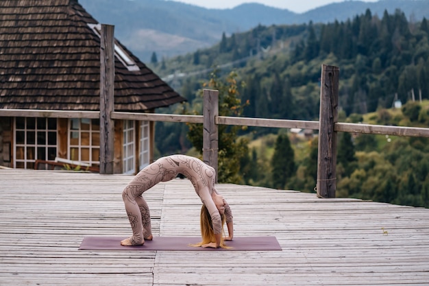 Una mujer practica yoga por la mañana en una terraza al aire libre.