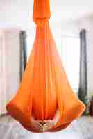 Foto gratuita mujer practicando aero yoga en hamaca naranja