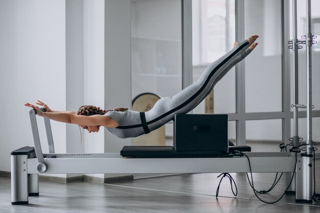 Mujer practicando pilates en un reformador de pilates