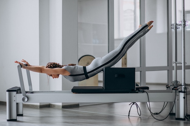 Mujer practicando pilates en un reformador de pilates