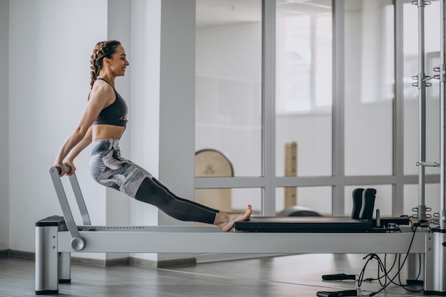 Mujer practicando pilates en un reformador de pilates