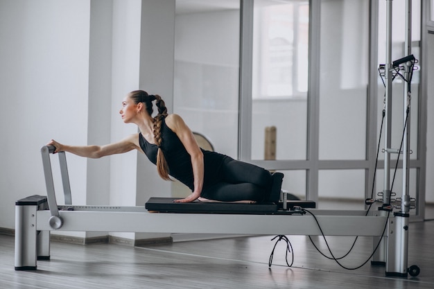 Mujer practicando pilates en un reformador de pilates