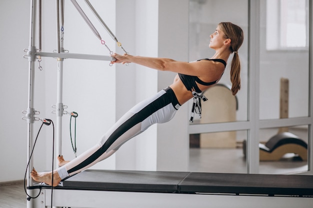 Mujer practicando pilates en un reformador de pilates