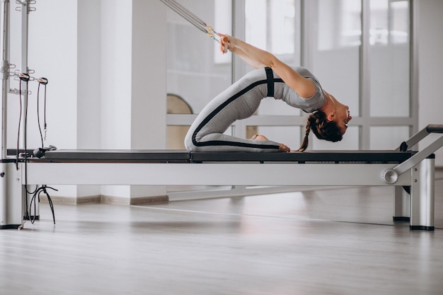 Mujer practicando pilates en un reformador de pilates