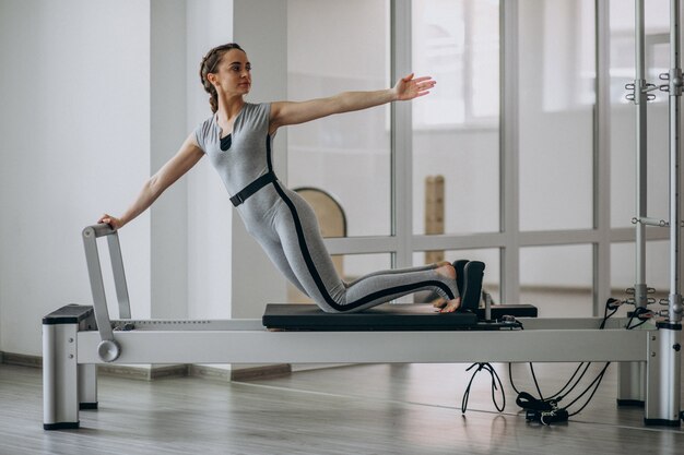 Mujer practicando pilates en un reformador de pilates