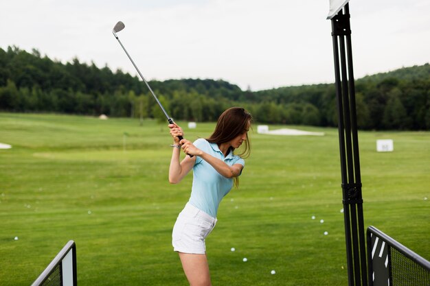 Mujer practicando swing de golf afuera