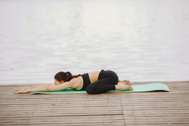 Mujer practicando yoga avanzado por el agua