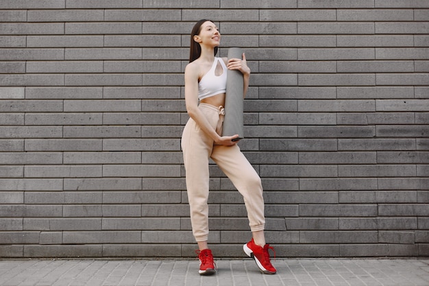 Mujer practicando yoga avanzado contra un muro urbano oscuro