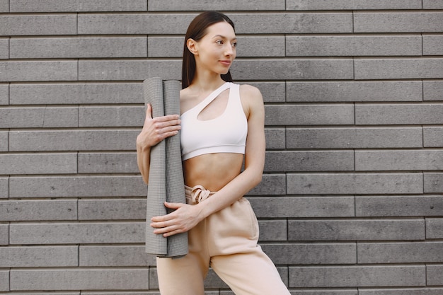 Mujer practicando yoga avanzado contra un muro urbano oscuro