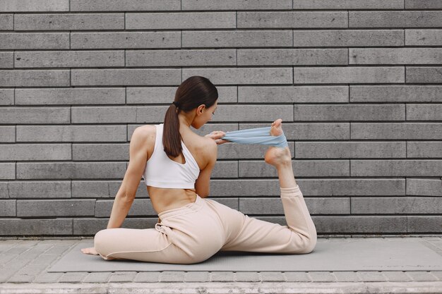 Mujer practicando yoga avanzado contra un muro urbano oscuro