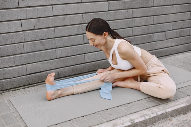 Mujer practicando yoga avanzado contra un muro urbano oscuro