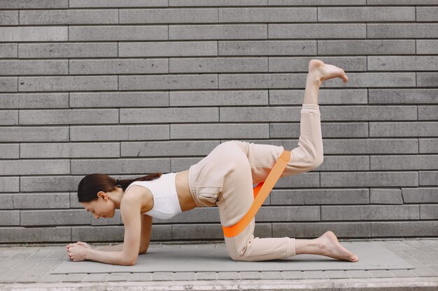 Mujer practicando yoga avanzado contra un muro urbano oscuro