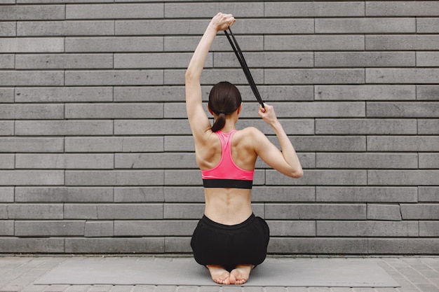 Mujer practicando yoga avanzado contra un muro urbano oscuro