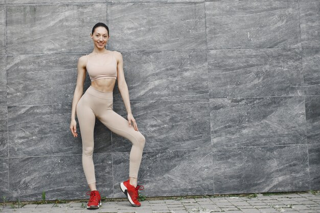 Mujer practicando yoga avanzado contra un muro urbano oscuro