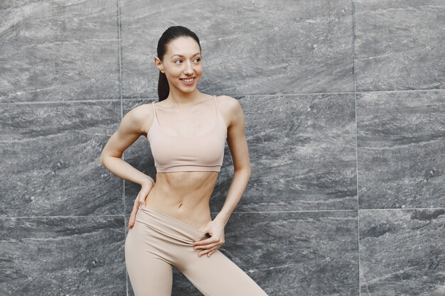 Mujer practicando yoga avanzado contra un muro urbano oscuro