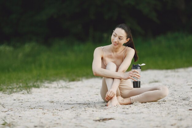 Mujer practicando yoga avanzado en una playa de verano