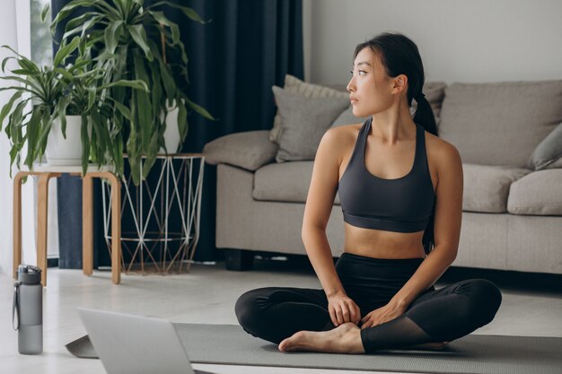 Mujer practicando yoga en estera en casa