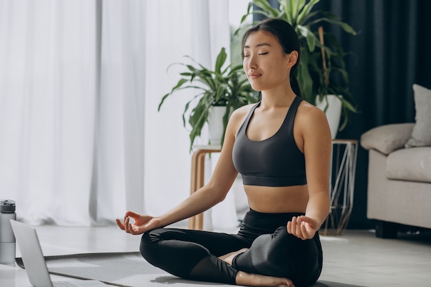 Mujer practicando yoga en estera en casa