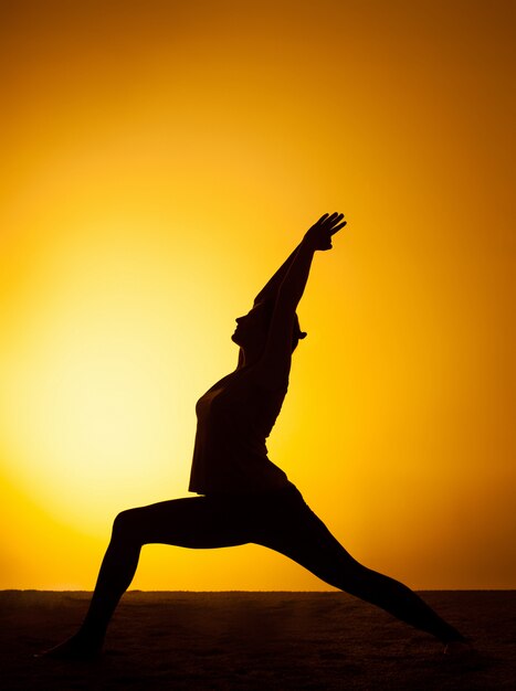 La mujer practicando yoga en la luz del atardecer