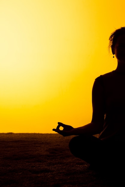 La mujer practicando yoga en la luz del atardecer