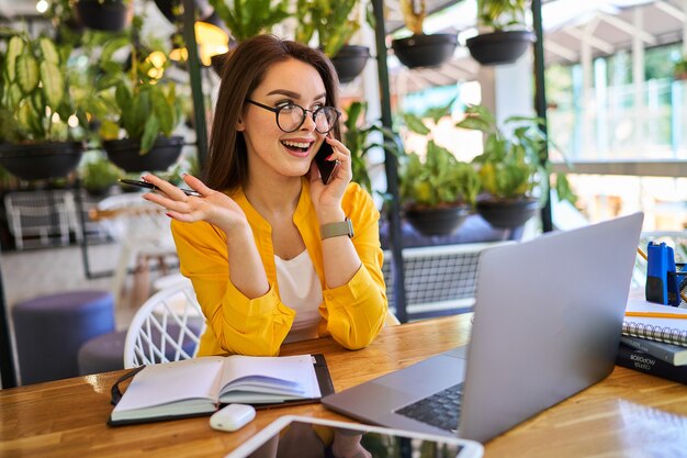 Mujer preety joven que trabaja en casa y que habla el teléfono móvil.