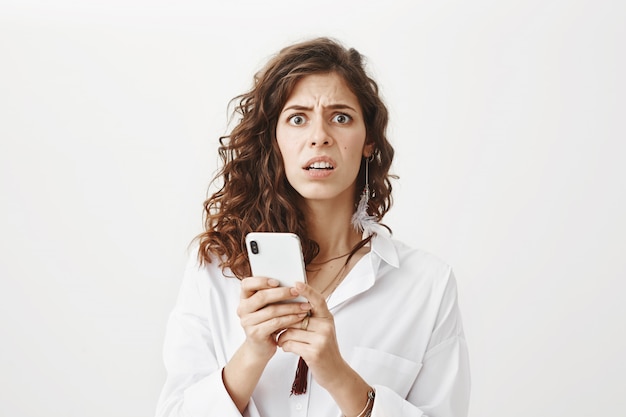 Mujer preocupada y confundida leyendo un extraño mensaje en el teléfono móvil