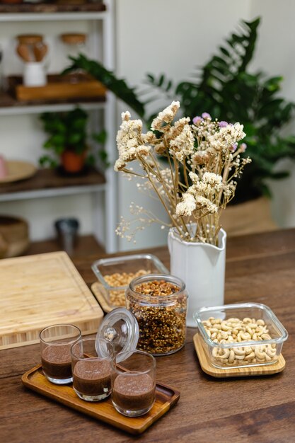 Una mujer prepara budín de chía en la cocina, colocando la capa inferior de leche de almendras, cacao y semillas de chía.