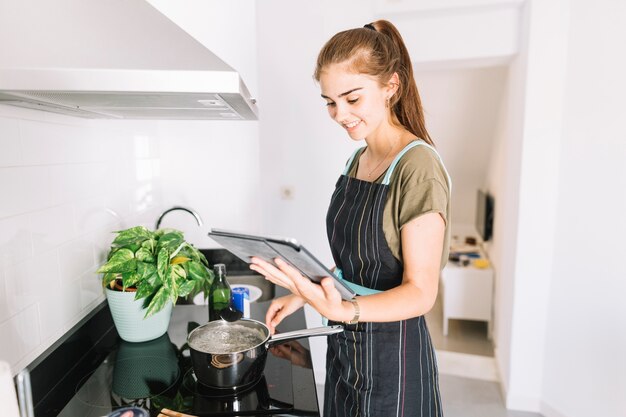 Mujer preparando comida mirando la receta en la tableta digital