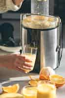 Foto gratuita mujer preparando jugo de naranja fresco para el desayuno en la cocina