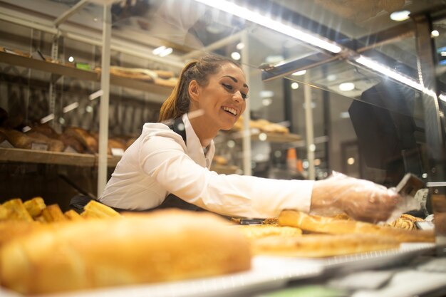 Mujer preparando pan para la venta en el departamento de panadería del supermercado