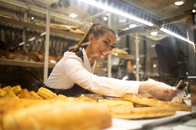 Mujer preparando pasteles para la venta en el departamento de panadería del supermercado