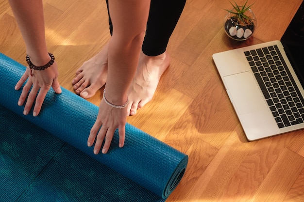 Mujer preparando su tapete para una clase de yoga en línea en casa