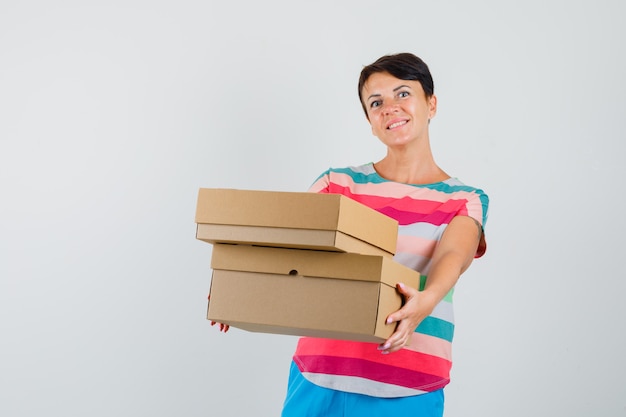Mujer presenta cajas de cartón en camiseta a rayas y mirando alegre