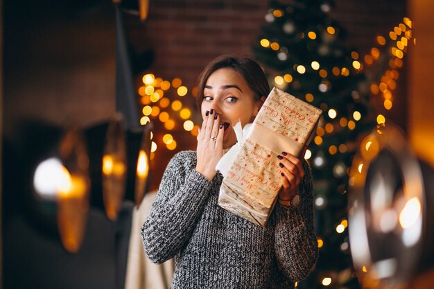 Mujer, con, presentes, delante de, árbol de navidad